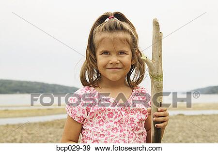 Girl holding driftwood at the beach View Large Photo Image Stock Photo - Girl holding driftwood at the beach. Fotosearch