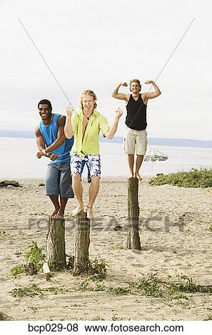 Men flexing their muscles at the beach View Large Photo Image Stock Photo - Men flexing their muscles at the beach. Fotosearch