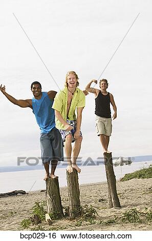 Men flexing their muscles at the beach View Large Photo Image Stock Photograph - Men flexing their muscles at the beach. Fotosearch
