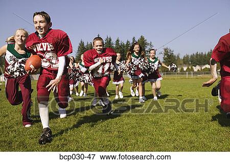 Players and cheerleaders running onto football field View Large Photo Image Stock Photo - Players and cheerleaders running onto football field. Fotosearch