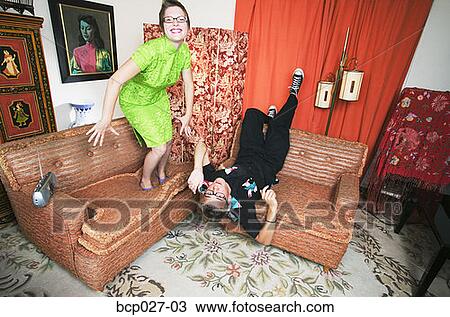 Stock Image - Couple dancing on living room furniture. Fotosearch