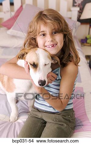 Girl hugging dog in bedroom View Large Photo Image Picture - Girl hugging dog in bedroom. Fotosearch