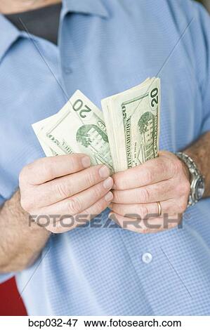Picture - Man holding American currency. Fotosearch - Search Stock Photography, Photos, Prints, Images, and Photo Clipart