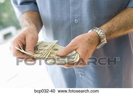 Stock Image - Man holding American currency. Fotosearch