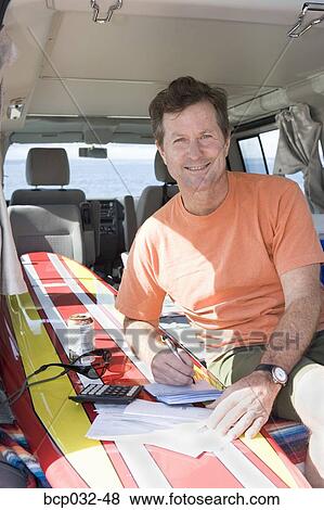 Stock Photo - Man writing checks in his van. Fotosearch