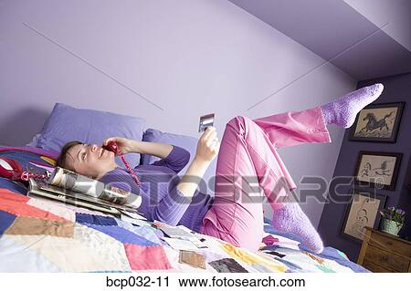 Woman holding credit card and talking on phone View Large Photo Image Stock Image - Woman holding credit card and talking on phone. Fotosearch