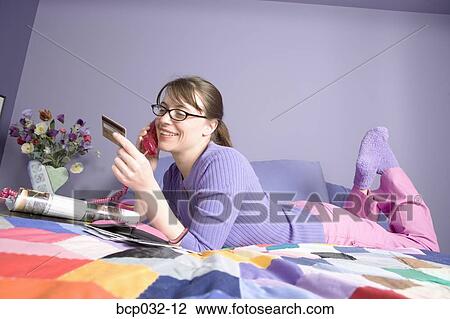 Woman holding credit card and talking on phone View Large Photo Image Stock Image - Woman holding credit card and talking on phone. Fotosearch