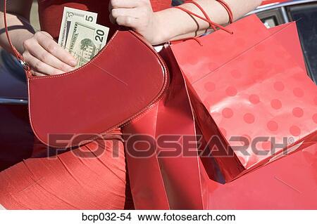 Woman holding money and shopping bags View Large Photo Image Picture - Woman holding money and shopping bags. Fotosearch
