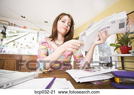 Stock Image - Woman looking at bills in mail. Fotosearch