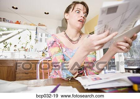 Stock Photo - Woman looking at bills in mail. Fotosearch