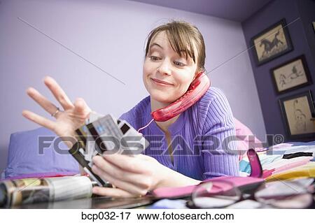 Woman on the phone choosing credit card View Large Photo Image Stock Photo - Woman on the phone choosing credit card. Fotosearch