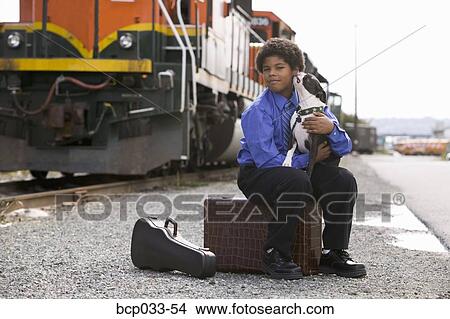 Boy sitting on suitcase holding dog View Large Photo Image Picture - Boy sitting on suitcase holding dog. Fotosearch