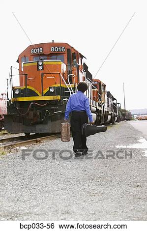 Stock Photograph - Boy walking towards train with baggage. Fotosearch