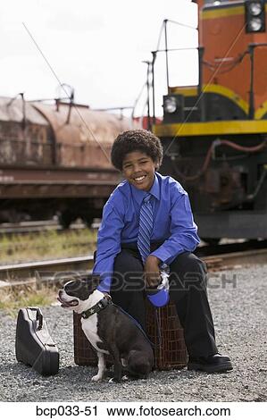 Stock Image - Boy with luggage and Boston Terrier. Fotosearch