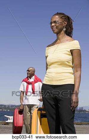 Stock Image - Couple on dock with luggage. Fotosearch