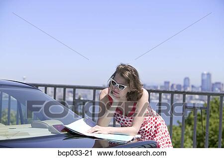 Woman leaning on car reading map View Large Photo Image Stock Image - Woman leaning on car reading map. Fotosearch