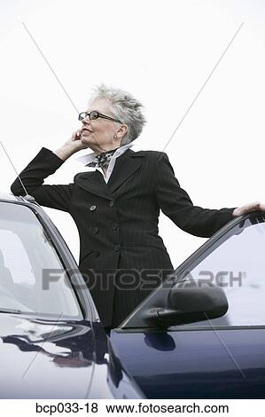 Woman next to car using mobile phone View Large Photo Image Stock Photo - Woman next to car using mobile phone. Fotosearch