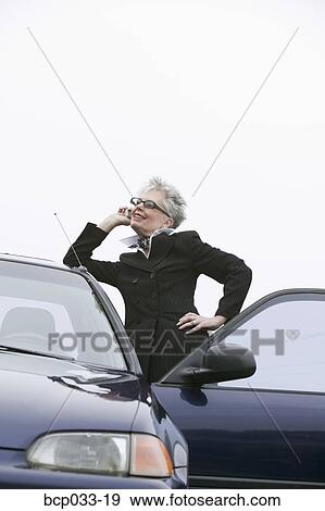 Woman next to car using mobile phone View Large Photo Image Stock Photo - Woman next to car using mobile phone. Fotosearch