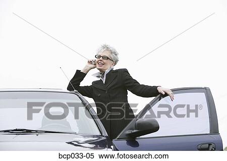 Woman next to car using mobile phone View Large Photo Image Stock Photography - Woman next to car using mobile phone. Fotosearch