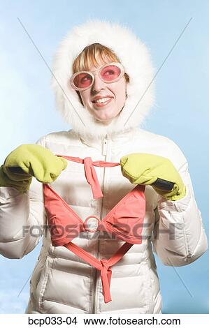 Picture - Woman wearing parka holding bikini top. Fotosearch