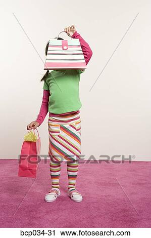 Stock Image - Girl holding purse in front of face. Fotosearch