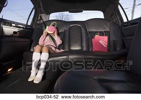 Stock Image - Girl in limousine hiding face with purse. Fotosearch