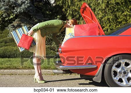 Woman looking in trunk of car View Large Photo Image Stock Image - Woman looking in trunk of car. Fotosearch