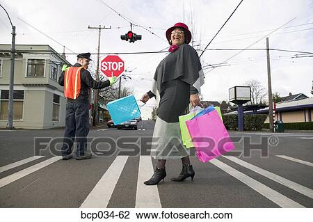 Stock Image - Woman with shopping bags crossing street. Fotosearch