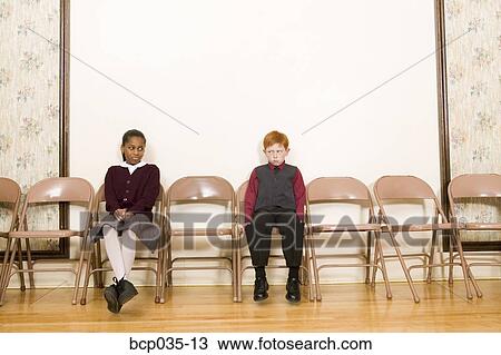 Girl and boy sitting in chairs against wall View Large Photo Image Stock Image - Girl and boy sitting in chairs against wall. Fotosearch
