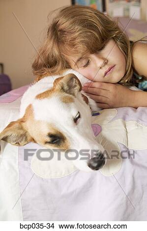 Girl and pet dog lying on bed View Large Photo Image Picture - Girl and pet dog lying on bed. Fotosearch