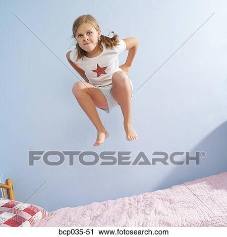 Stock Image - Girl jumping on bed. Fotosearch