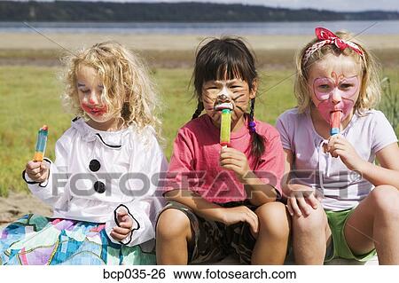 Stock Photograph - Girls eating frozen treats outdoors. Fotosearch