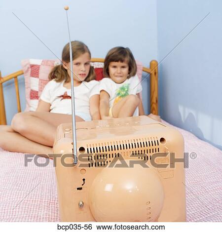 Girls watching television in bed View Large Photo Image Stock Photograph - Girls watching television in bed. Fotosearch
