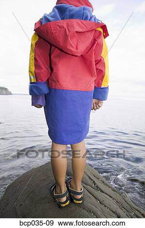 Stock Photo - Rear view of child standing on rock. Fotosearch
