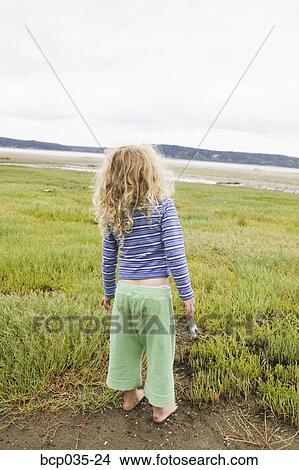 Picture - Young girl standing alone outdoors. Fotosearch
