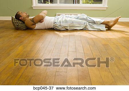 Man lying on floor at home View Large Photo Image Stock Photo - Man lying on floor at home. Fotosearch