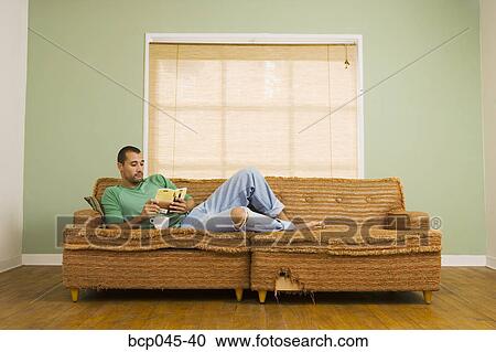 Man on sofa reading book View Large Photo Image Stock Image - Man on sofa reading book. Fotosearch