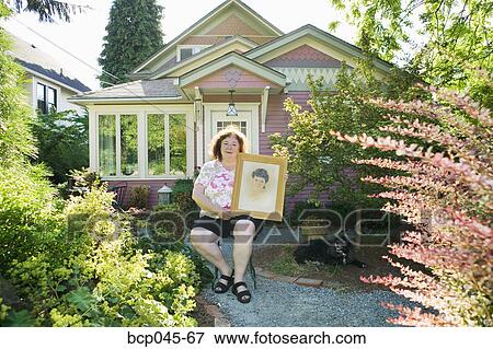 Woman holding portrait of herself as a girl View Large Photo Image Stock Photo - Woman holding portrait of herself as a girl. Fotosearch