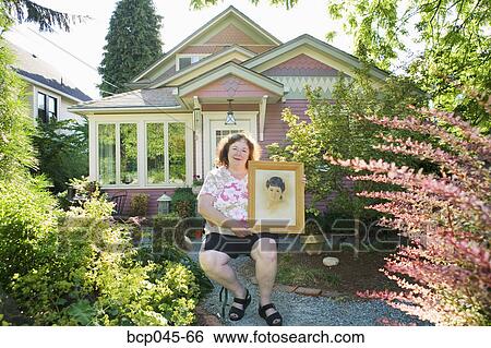 Woman holding portrait of herself as a girl View Large Photo Image Stock Photograph - Woman holding portrait of herself as a girl. Fotosearch