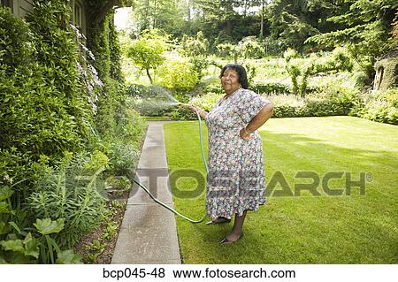 Stock Photo - Woman watering her garden. Fotosearch