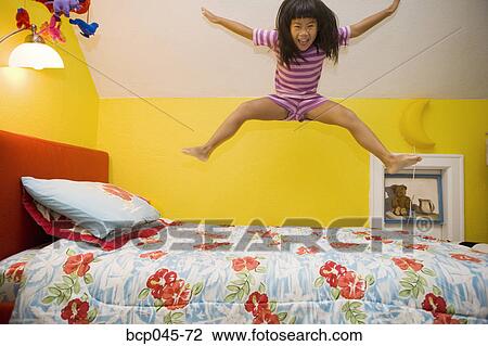 Young girl jumping on bed View Large Photo Image Stock Image - Young girl jumping on bed. Fotosearch