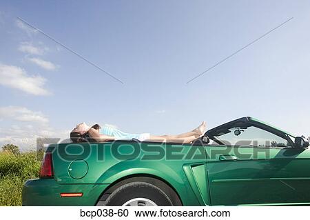 Stock Image - Girl relaxing on car. Fotosearch