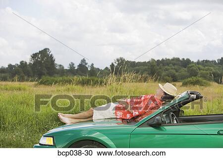 Man resting on a car View Large Photo Image Stock Image - Man resting on a car. Fotosearch