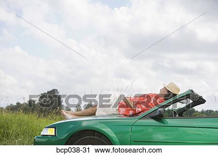 Man resting on a car View Large Photo Image Stock Image - Man resting on a car. Fotosearch