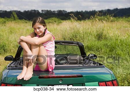 Picture - Portrait of girl sitting on car. Fotosearch