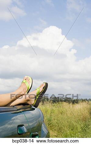 Picture - Woman resting feet on car. Fotosearch