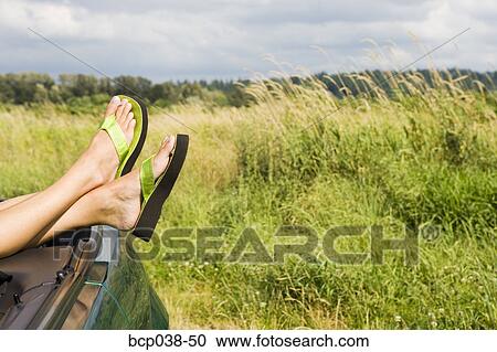 Stock Image - Woman resting feet on car. Fotosearch