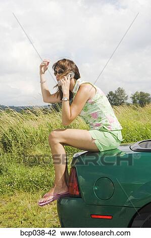 Woman sitting on car and talking on mobile phone View Large Photo Image Stock Image - Woman sitting on car and talking on mobile phone. Fotosearch