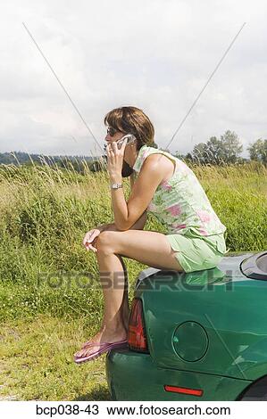 Woman sitting on car and talking on mobile phone View Large Photo Image Stock Image - Woman sitting on car and talking on mobile phone. Fotosearch