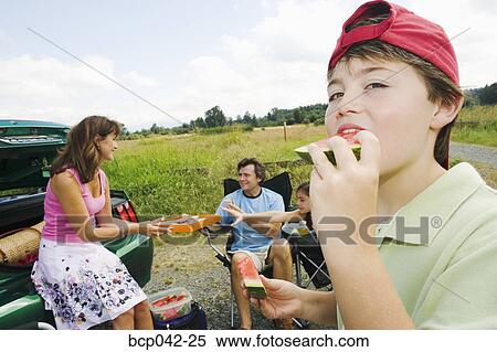 Boy eating watermelon at family picnic View Large Photo Image Stock Photography - Boy eating watermelon at family picnic. Fotosearch